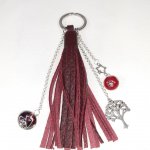 Bijou de sac, pompon cuir coloris bordeaux avec perles en verre filé.