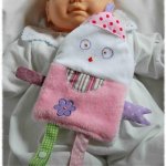 Doudou plat polaire rose et coton différents texture en forme de bonhomme grand sourire et yeux qui louchent brodés