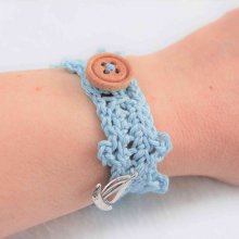 Bracelet adulte crocheté main avec un fil coton bleu clair, un bouton en bois rond 4 trous et une breloque forme bateau