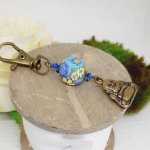 porte clé pendentif bouddha bronze et sublime perle violet faite à la main avec marguerites jaunes/jaune