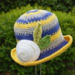 Chapeau poupée jaune bleu et gris avec rose blanche et feuilles en décoration
