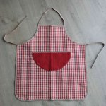 Tablier enfant en coton épais à carreaux rouges et beige, poche rouge et liens marron