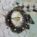 Collier Oiseau des Jardins s’inspire d’un oiseau dans la nature. Sur une base d’un pendentif, ce motif est orné de cristaux : nœud et cabochons aux nuances cristal et Péridot. Monté sur chaîne Laiton