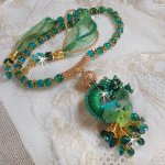 Collier Green Iris brodé avec du coton DMC Vert sur un anneau en bois avec fleurs Lucites, gouttes en cristal. Le tout est monté avec perles rondes craquelées, ruban organza et fermoir en argent 925