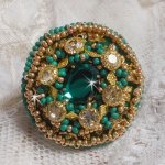 Bague Green Iris brodée avec un cabochon Emeraude ornée de chatons fleurs cristal sertis, rocailles Vert Opaque et Gold. Montés sur feutrine Verte et sur une bague plateau Dorée, un style Contemporain