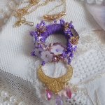 Pendentif Laureline brodé avec un fil coton Violet, monté avec des cristaux, fleurs lucites, perles nacrées, calottes dorées, rocaille, pendentif sur une chaîne en plaqué Or. Un voile de douceur