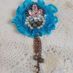 Broche Belle Epoque Haute-Couture est brodée avec des Cristaux de Swarovski, des perles rondes nacrées, des breloques, un ruban et des rocailles