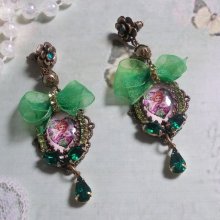 BO Cœur d’Anges avec des cabochons d’un petit ange ornés d’une chaîne strass, navettes, poires et cabochons en Cristal. S’ajoute des rubans organza sur pendentifs et clous en forme de fleurs.