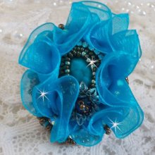 Bague Ilycia Charming brodée avec un cabochon facetté Bleu Turquoise, fleur en Cristal, chatons, rocailles Gold et Bronze. Le tout est monté sur un support de bague couleur Or en laiton