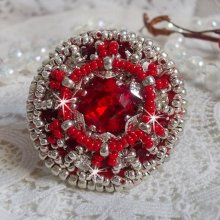 Bague Drigon Red brodée avec un cabochon carré Rouge sur une estampe Argentée. Ornée de chatons en Cristal puis modelée avec des rocailles et perles. Le tout est monté sur une bague réglable argentée 