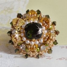 Bague L’Oiseau des Iles Vert Dorée avec un cabochon Vert sur une estampe dorée ornée de cristaux : toupies et chatons. Les perles rondes nacrées Ivoire et Olivine complète cette bague réglable. 